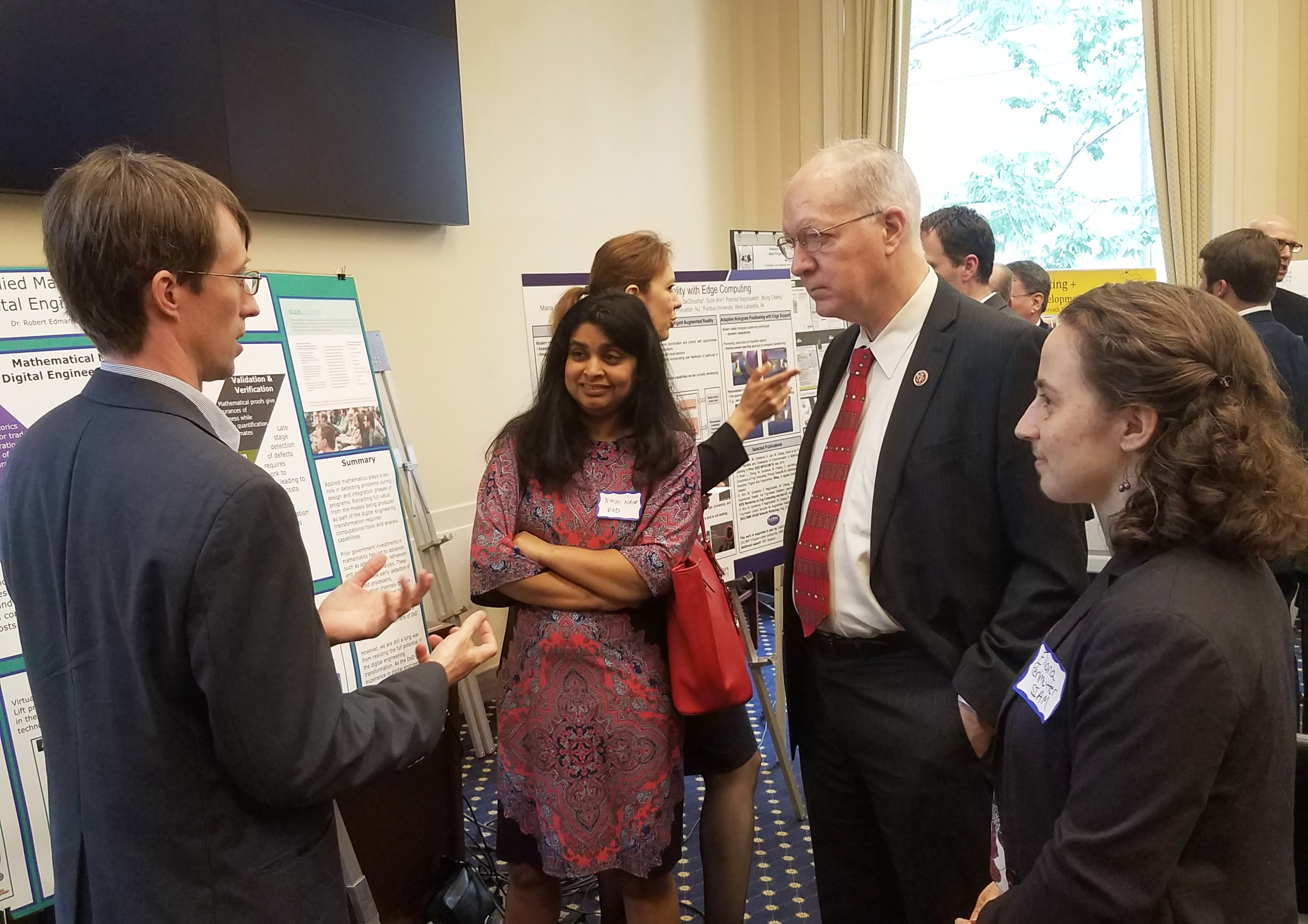SIAM Science Policy Fellowship recipient Robert Edman (Adventium Labs) presents a poster illustrating the importance of applied mathematics to the Department of Defense mission at the second annual Science, Technology, & Innovation Exchange briefing, which took place in May on Capitol Hill in Washington, D.C. Here he converses with Bindu Nair (Office of the Secretary of Defense) and Representative Bill Foster (D-IL). Photo courtesy of Eliana Perlmutter.