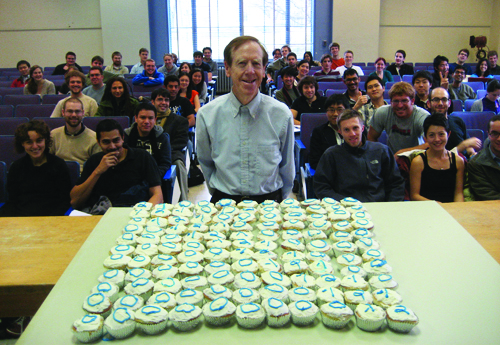 Gilbert (Gil) Strang poses in front of 121 cupcakes with his favorite -1, 2, -1 matrix in icing on top. Students in his undergraduate linear algebra class provided the cupcakes several years ago in honor of his birthday. Photo courtesy of Gil Strang.